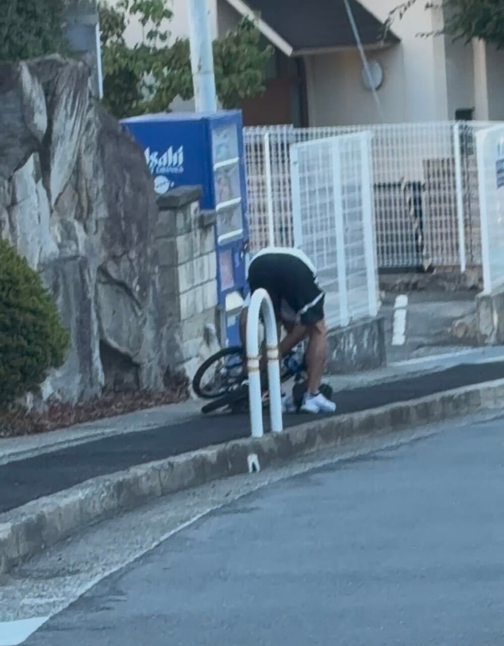 壊れた自転車を折り畳む後ろ姿。